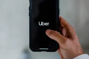 man holding a phone, using the Uber app.